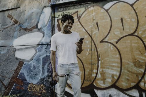 black man laughing on phone in front of mural