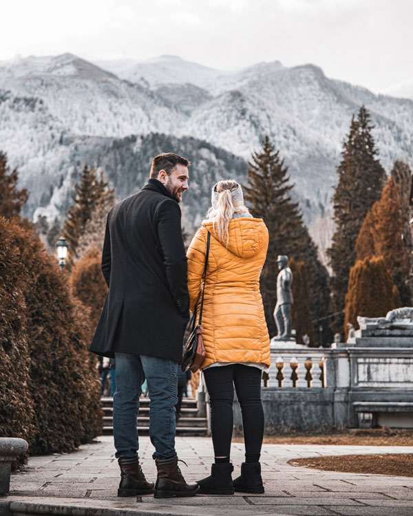 Couple with backs facing the camera but looking at the snowy mountains