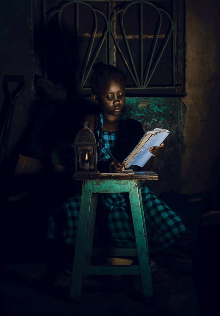 girl writing in a book on a stool 