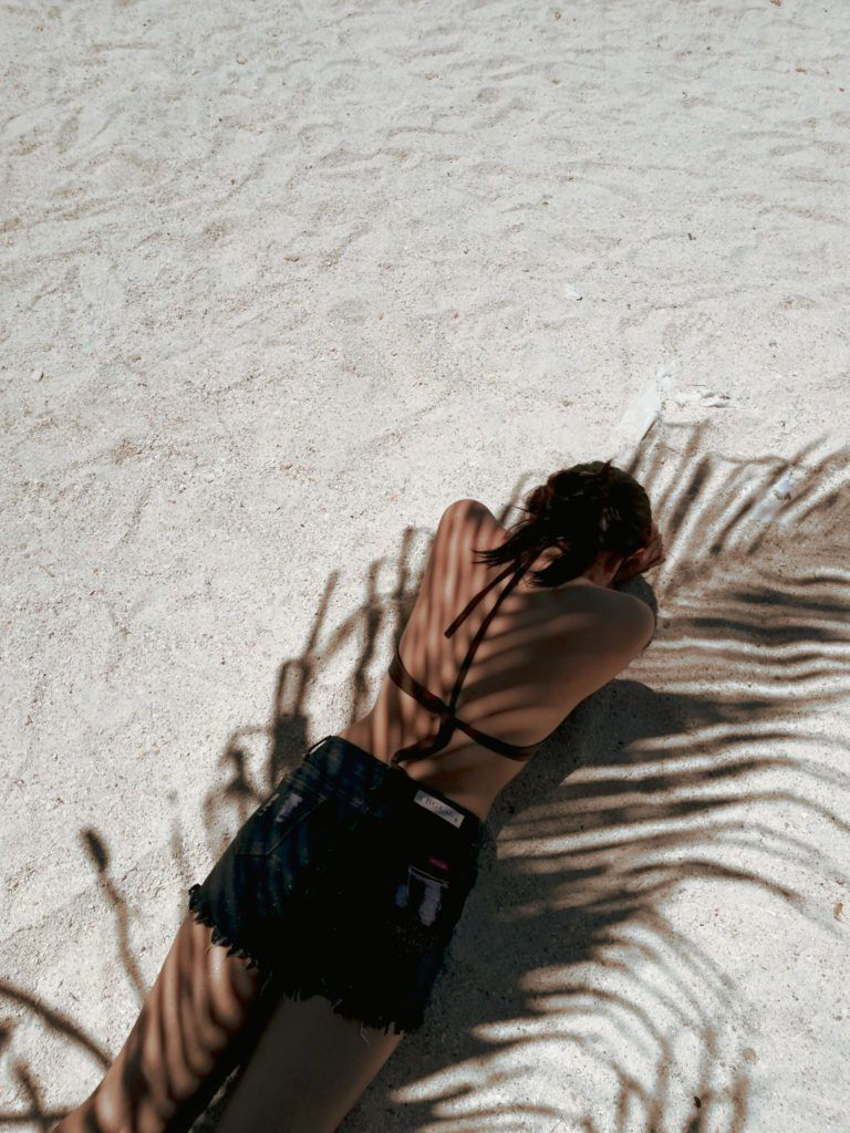 female lying facedown on the beach