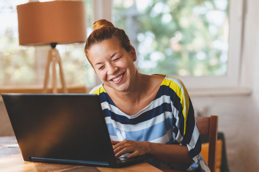 Female on laptop typing and smiling