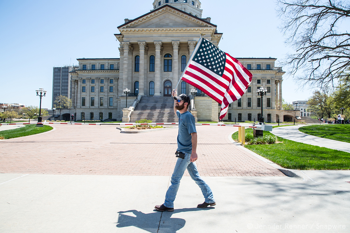 man holding a flag walking in front a government building