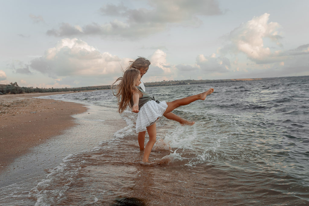 two people flicking water into the ocean with their feet