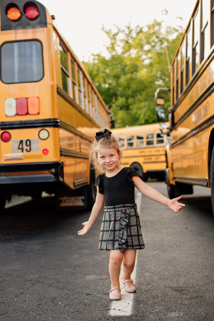 girl walking in between two school buses