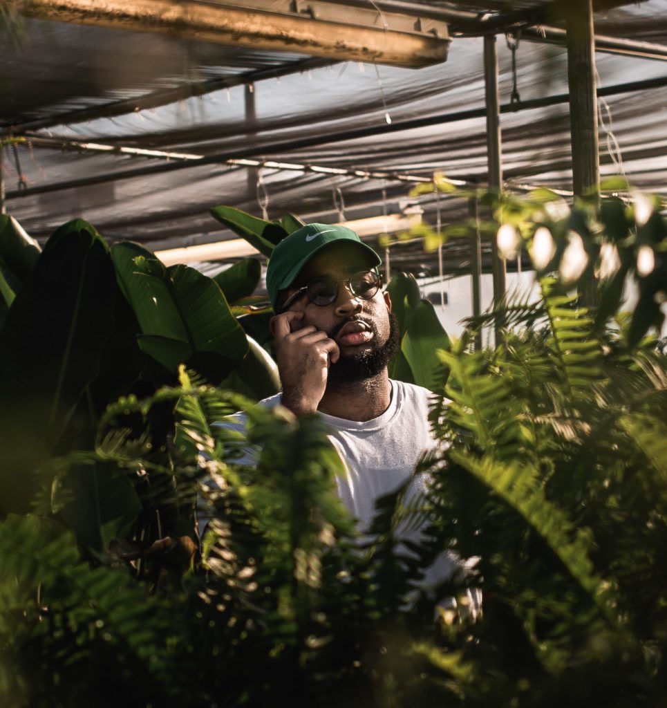 male on a phone surrounded by plants