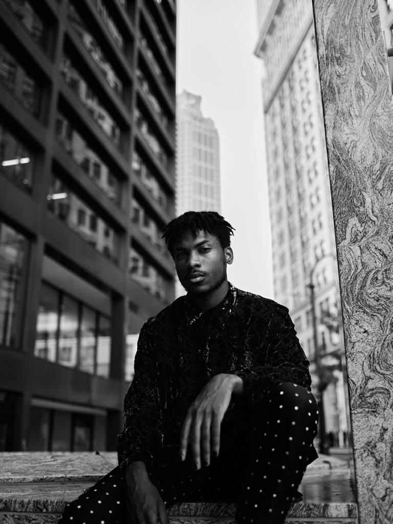 portrait guy sitting in front of buildings