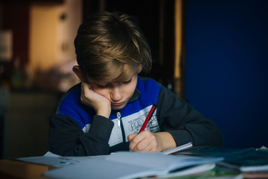 kid sitting down writing in a book