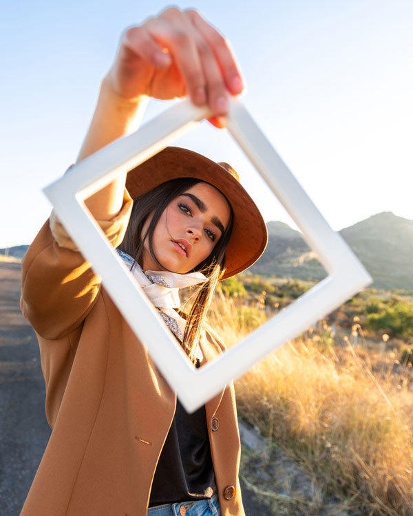 Close up of woman holding up a picture frame looking through it