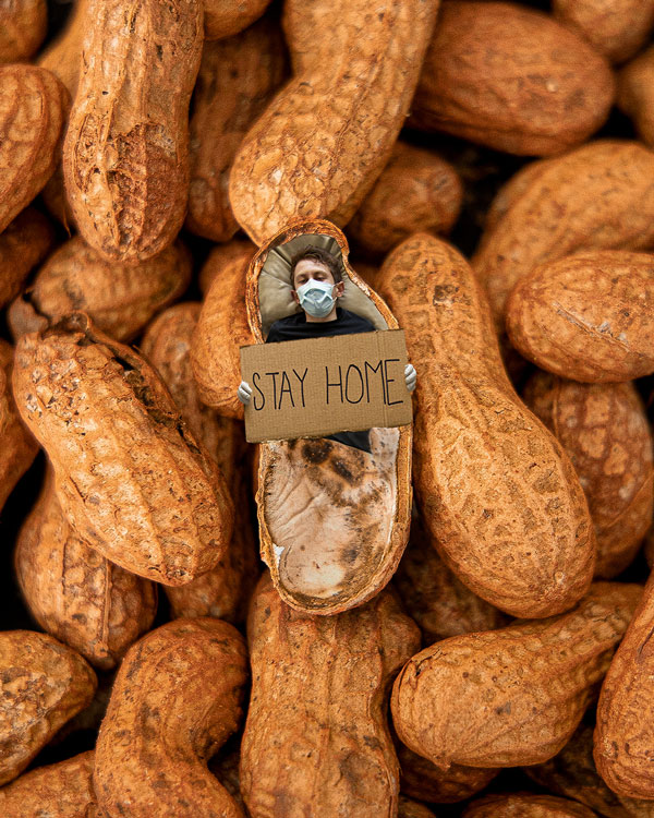 Man laying inside of a peanut with stay home sign wearing a mask and gloves