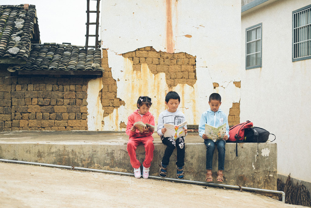 3 kids sitting on a wall