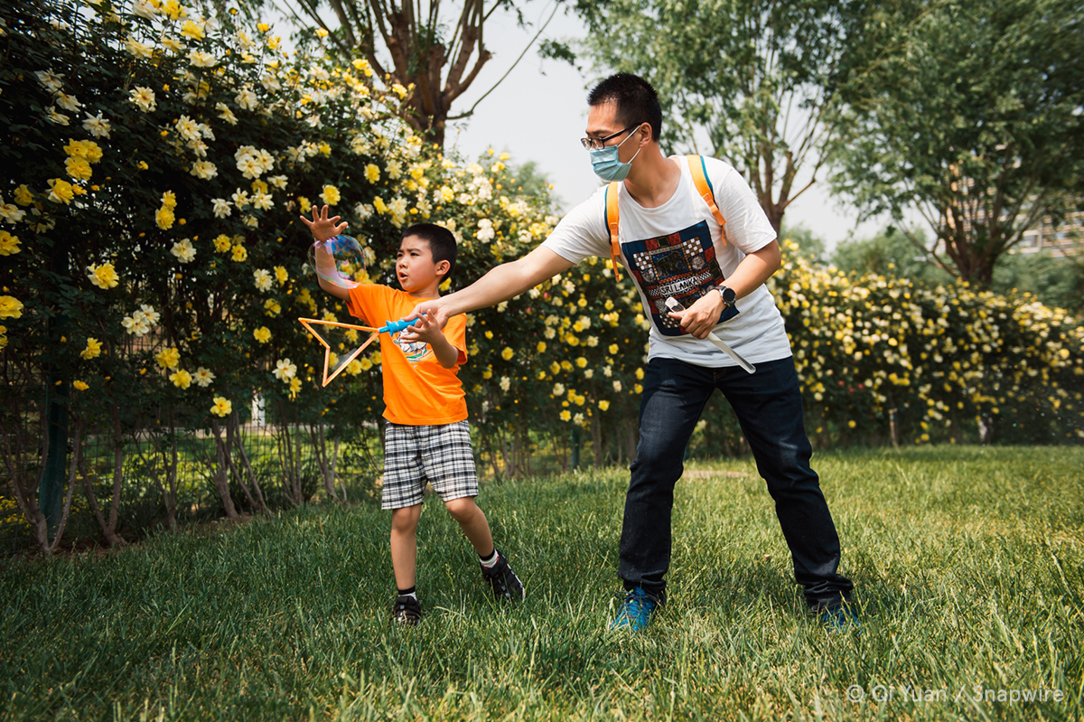 man and kid playing with bubbles in grass