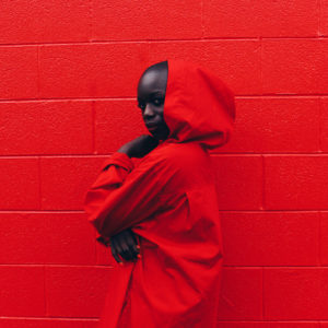 portrait girl in red hoodie in front of a red wall