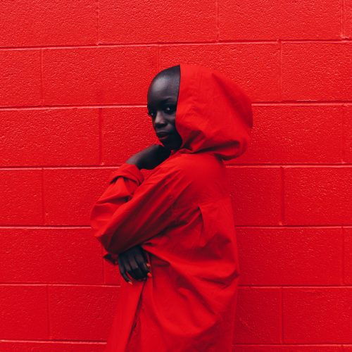 portrait girl in red hoodie in front of a red wall