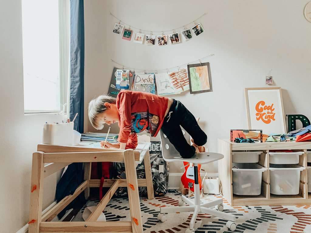 kid standing on chair writing