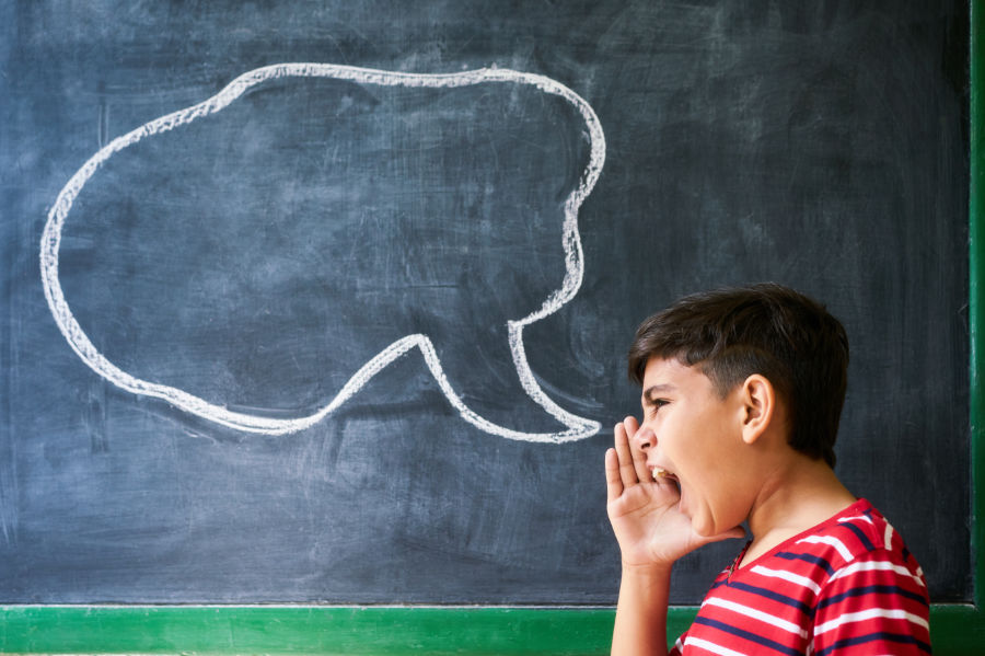 young boy yelling with talking bubble on chalkboard