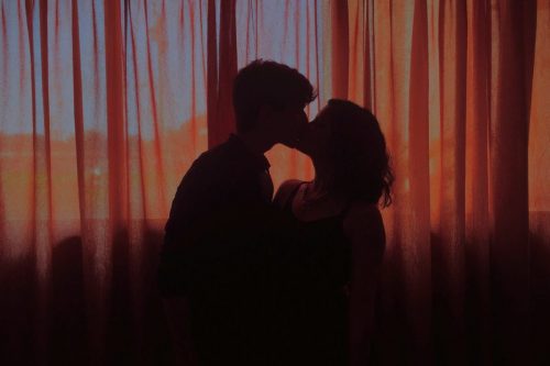 young couple kissing room with red curtains